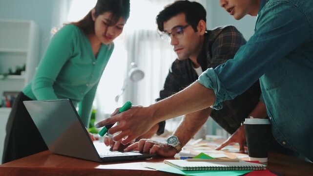 Skilled business team looking at laptop and pointing logo design while making decision to choosing main theme color and planning marketing campaign. Smart start up group working together. Symposium.