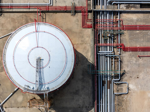 Aerial view of LNG silos featuring a large circular storage tank with red markings and a complex network of industrial pipes in Matosinhos, Porto, Portugal.