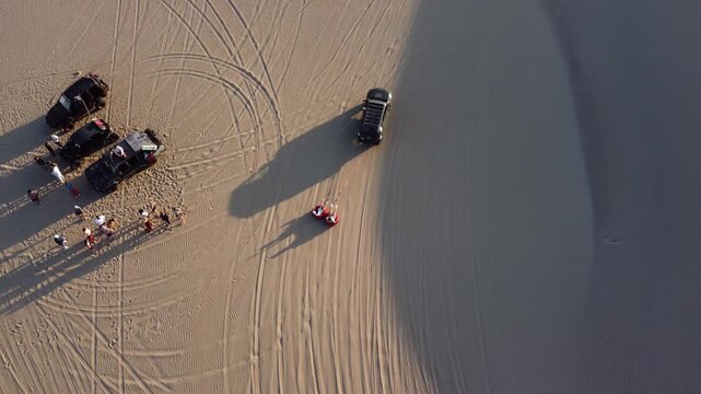 Dune buggy towing sandboarders in huacachina desert