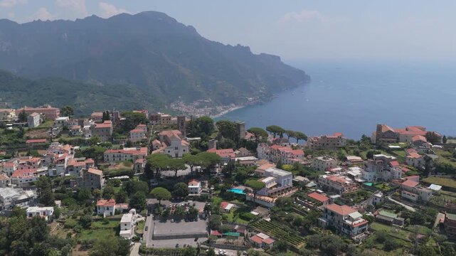 Aerial view of the historic town of Ravello with its stone buildings, lush gardens, and coastal cliffs overlooking the Tyrrhenian Sea in Ravello, Campania, Italy.