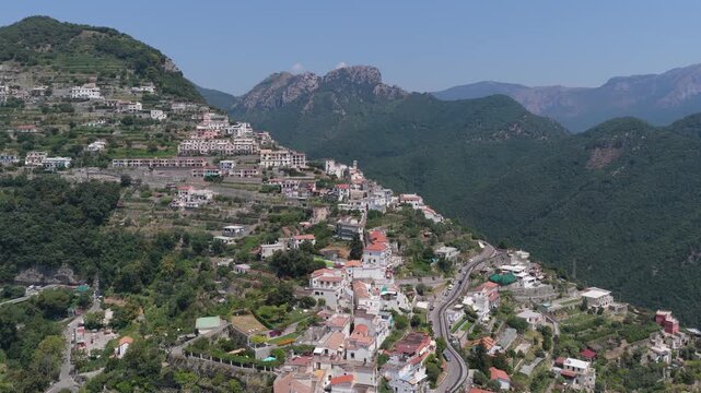 Aerial view of the historic town of Ravello nestled on the terraced mountain slopes with lush greenery and winding roads overlooking the Amalfi Coast in Ravello, Campania, Italy.