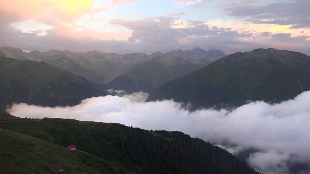 Timelapse mountain cabin above clouds in Huser Yaylasi, Rize, Turkey amid forest peaks.