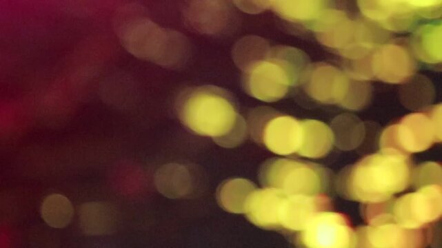 Abstract golden bokeh lights background with soft focus glowing yellow spots on dark burgundy background for festive celebration design