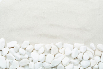 White pebble stones with sand as background, top view © Liami