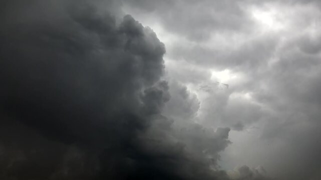 Dense cumulonimbus clouds break apart after storm revealing lighter sky and dramatic atmosphere.
