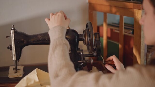 Preparation closeup threading antique sewing machine white woman carefully guides thread through needle eye, fabric pieces laid on tabletop, focused ritual of craft, patient hands