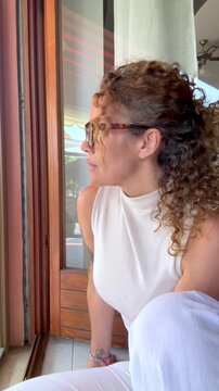 Mature woman looking thoughtfully out the window at home
