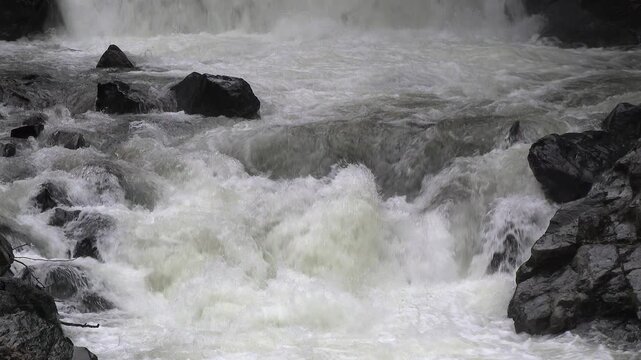 Foamy water flows through a narrow rocky gorge after a waterfall.