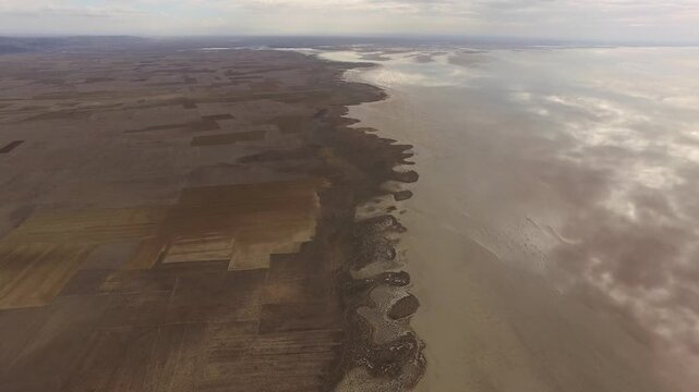 Kazakhstan Aral Lake shoreline stretches across sand, shallow water, and dry desert coast.