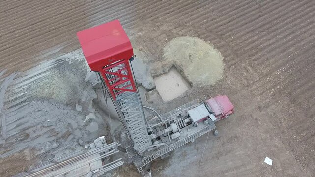 Aerial view of a drilling rig extracting groundwater from a flat alluvial plain farmland.