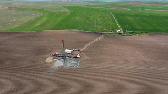 Aerial drilling rig extracts groundwater from a flat rural plain.