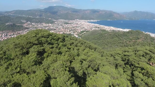 Aerial view of coastal city beside forest and sea in summer tourism destination region.