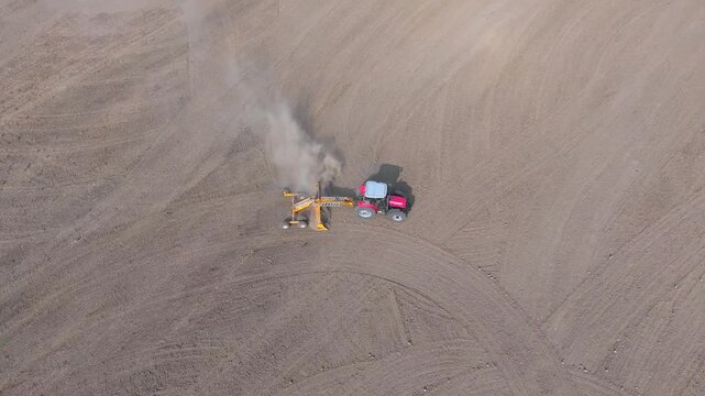 Aerial land leveling shows heavy machinery grading brown soil across a wide field.