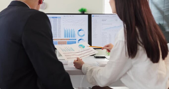 Analysts teamwork discuss finance data and dashboard. Colleagues review charts on computer screens and printouts, aligning analytics with metrics. Concept image of collaborative office analysis.