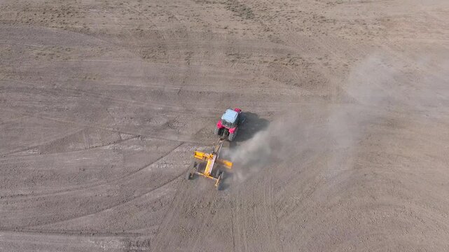 Aerial land leveling shows heavy machinery grading brown soil across a wide field.