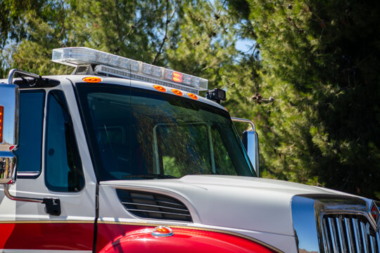Firemen and women practicing to put out fires on an abandoned house looking at the cab and lightbar on a fire truck to tell people to get out of the way.