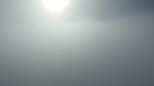 Vertical camera rises through dense fog and breaks above clouds symbolizing freedom and discovery.