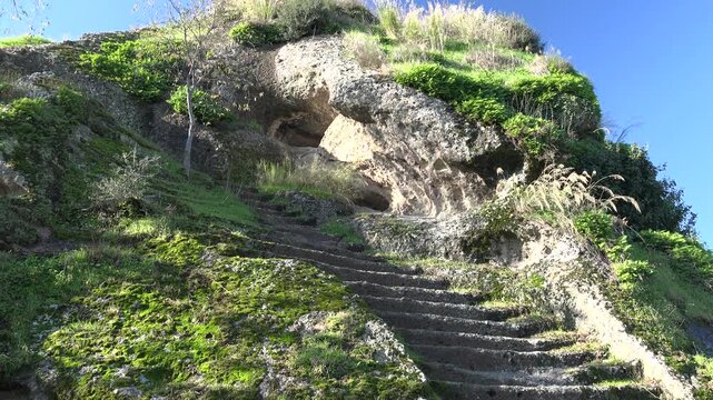 Ancient rock stairway carved into stone hillside leading toward prehistoric cave dwelling.
