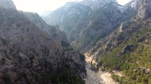 Aerial view of drought dried stream bed winding through forested Pakistan mountain valleys.