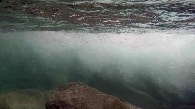 Underwater view of a fast flowing foamy mountain river showing powerful current and motion.