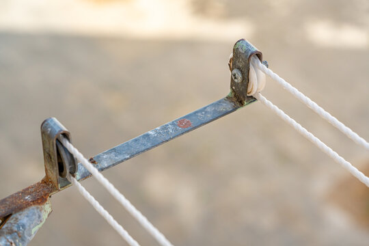 Metal clothesline support with detail of two pulleys and part of the ropes.