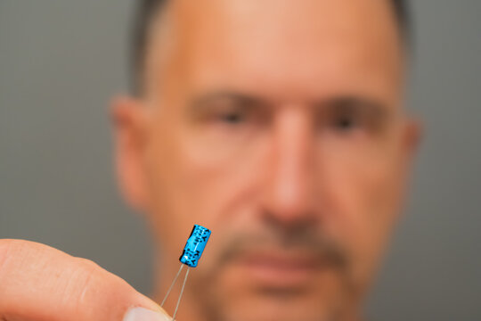 A male electrical engineer observes an electrolytic capacitor.