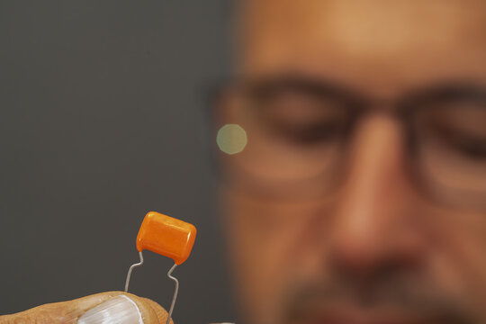 A male electrical engineer observes a polyester capacitor.
