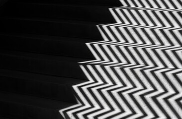 Naklejka premium Stark zigzag shadow pattern on dark, modern stairs