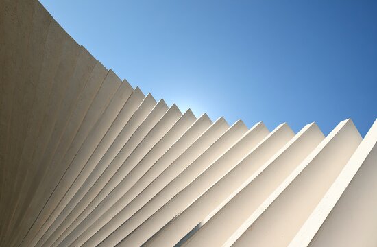 Curved geometric structure of pale concrete against a bright blue sky