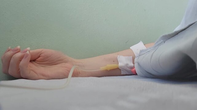 Patient hand with an intravenous IV catheter in a clinical ward. healthcare recovery, medical treatment, hospital care.