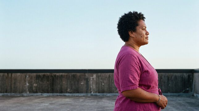 Woman standing on rooftop looking away representing diverse beauty and empowerment outdoors