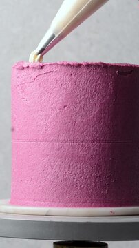 Piping buttercream border on a pink cake, process of decorating a pink cake with cream buttercream piping, process of decorating a pink vintage style cake