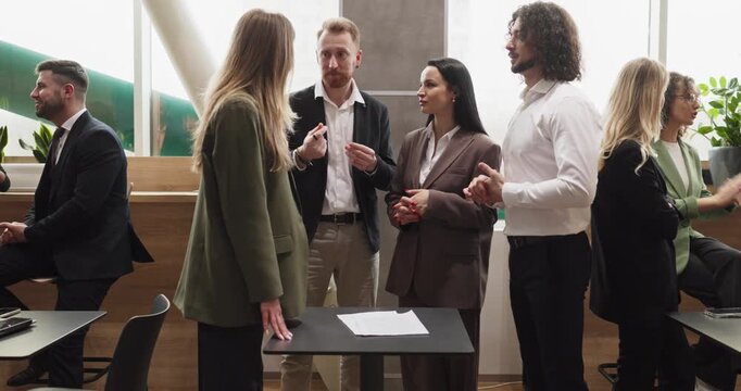 Business professionals networking in office meeting discussion. Colleagues and coworkers exchange ideas in small groups during a break. Focus on collaboration, communication, and partnership.