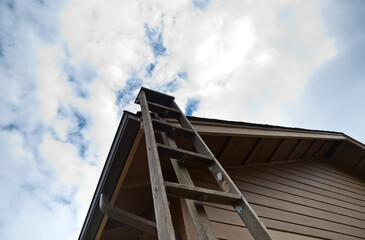 Extension ladder leaning against house roof © Jaime