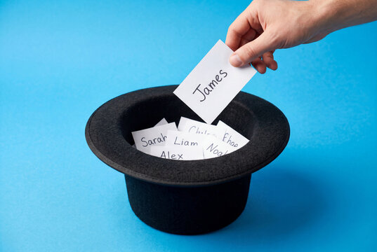 Hand drawing a name card from a black top hat for a random selection