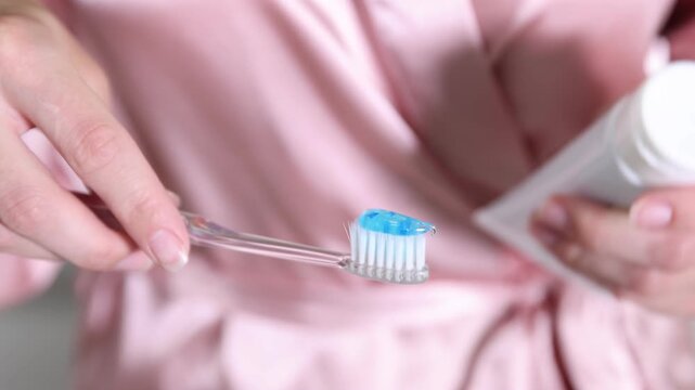 Woman applying toothpaste on toothbrush in bathroom, closeup