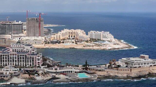 st julian's luxury seaside resorts aerial view modern developments rocky peninsula vivid water malta Mediterranean lifestyle luxury real estate clear blue sky turquoise sea aerial drone cinematography