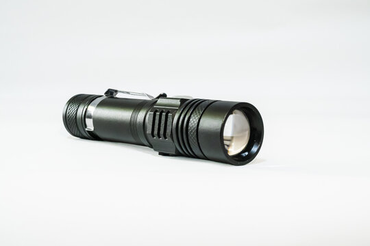 Black tactical LED flashlight with pocket clip isolated on a white background.