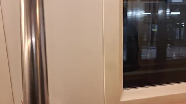 View from inside a modern metro bus while moving through the city with passenger handrails and modern interior visible.