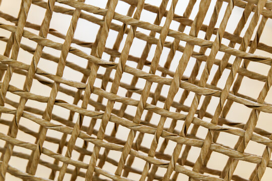 Macro detail of natural light brown woven twisted fiber mesh texture background pattern.