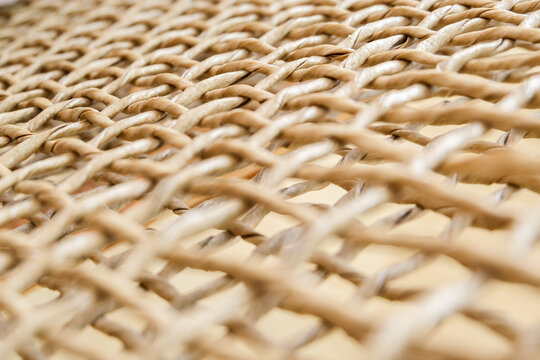 Macro detail of natural light brown woven twisted fiber mesh texture background pattern.