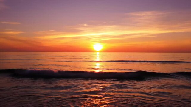 Dramatic orange sunset with calm ocean waves at the horizon line