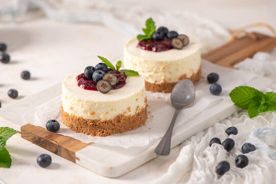 Two delicious mini cheesecakes with blueberry jam and fresh berries on a marble board