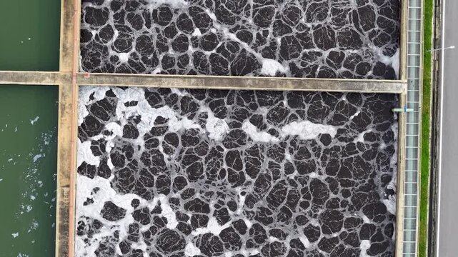 Top down drone shot of aeration basins with foamy sludge at wastewater treatment facility