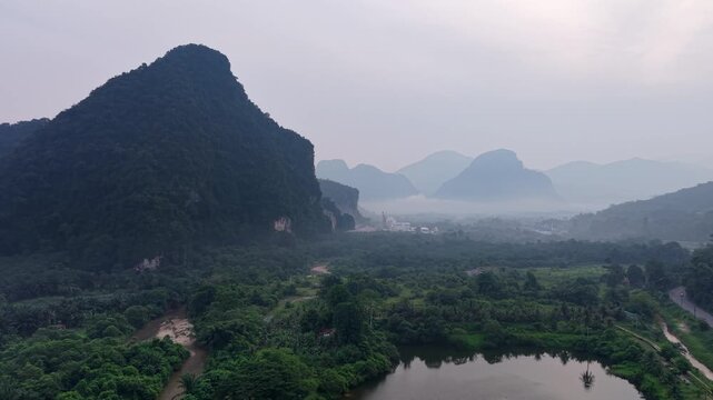 Aerial view captures misty mountains and a winding river through green valleys at Kampar, Perak