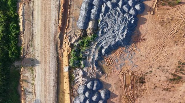 Aerial view shows concrete blocks stacked along a dirt road