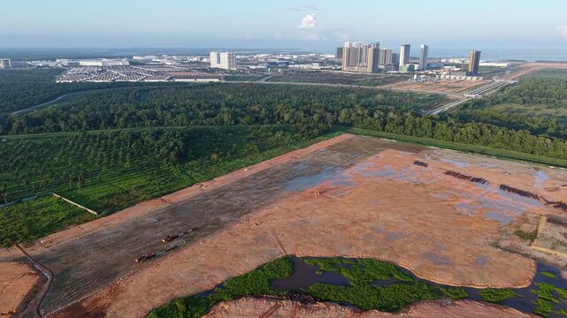 Sunrise illuminates a cleared brown field. Patches of water dot the dry earth