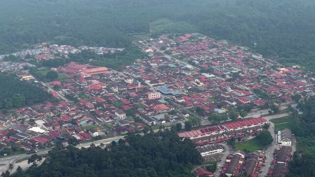 High angle drone shot showing dense red rooftops and surrounding forest in Kampar town.