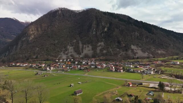 Most na Soči village and the Soča River in Slovenia's Soča Valley, with red-roof houses, forests and winter farmland beneath the Julian Alps, captured by drone.