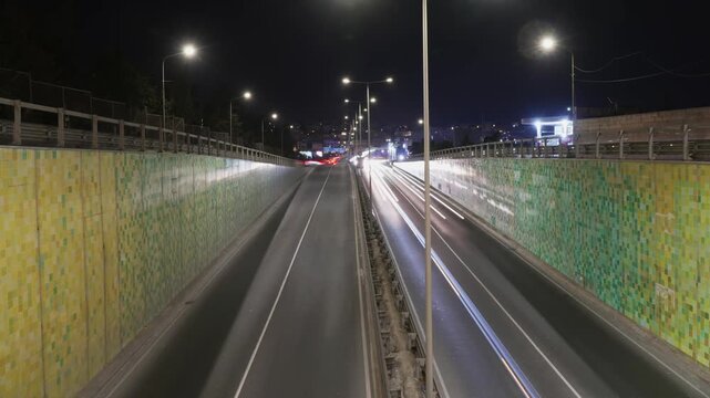 Msida, Malta traffic on Triq Mikiel Anton Vassalli at a tunnel exit with light trails and motion blur from cars on a busy arterial road at night in timelapse.